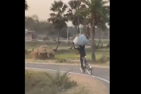 Youth carries grass on his head races on cycle