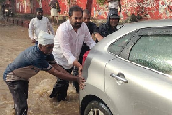 MLA Kotam Reddy helps to push vehicles stranded in rain water