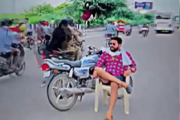 man sits on chair with parked bike in the middle of road in delhi for reel