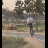 Youth carries grass on his head races on cycle