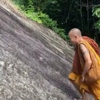 Monk climbs up steep mountain without a safety harness