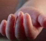 Mother dips babys fingers in hot oil  as it stops feeding 