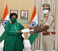Governor Tamilisai hands over a cheque for Rs 80,000 to Sub Inspector 